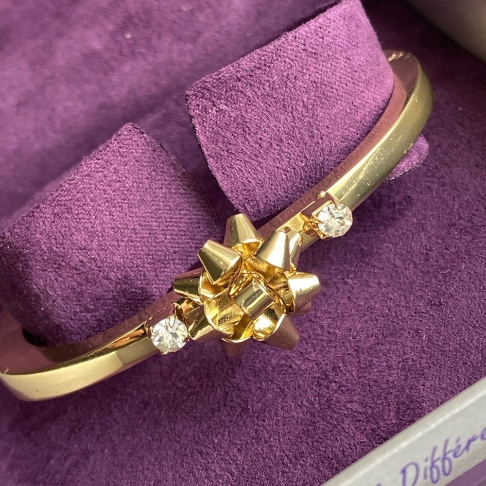 STUNNING gold tone hinged bracelet with bow and 2 crystals